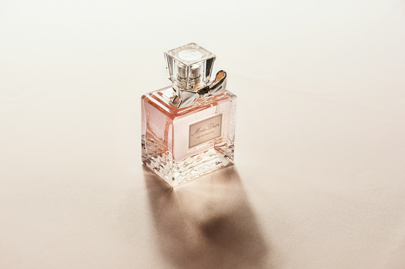 Perfume bottle casting a soft shadow on a cream surface